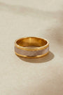 Gold ring with a textured band on a beige background