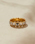Gold ring with pyramid-shaped stones on a beige background