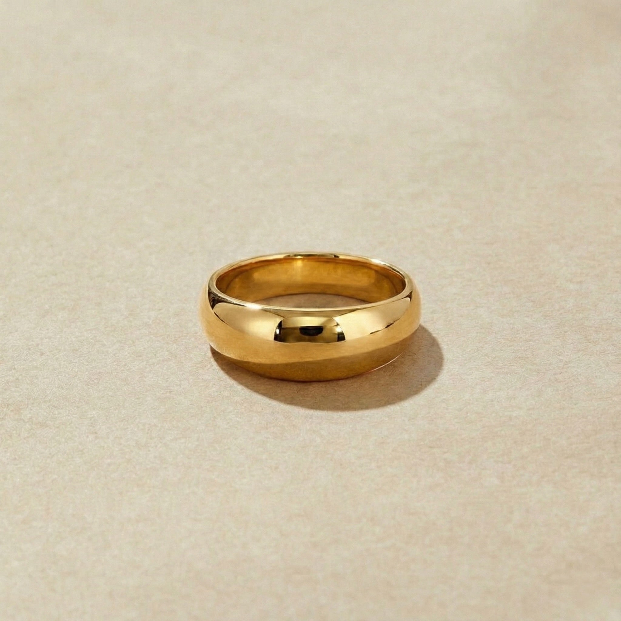 High polished gold ring on a beige background