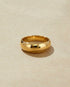 High polished gold ring on a beige background