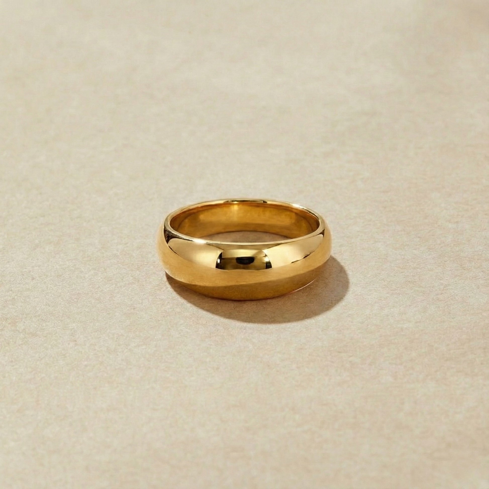 High polished gold ring on a beige background